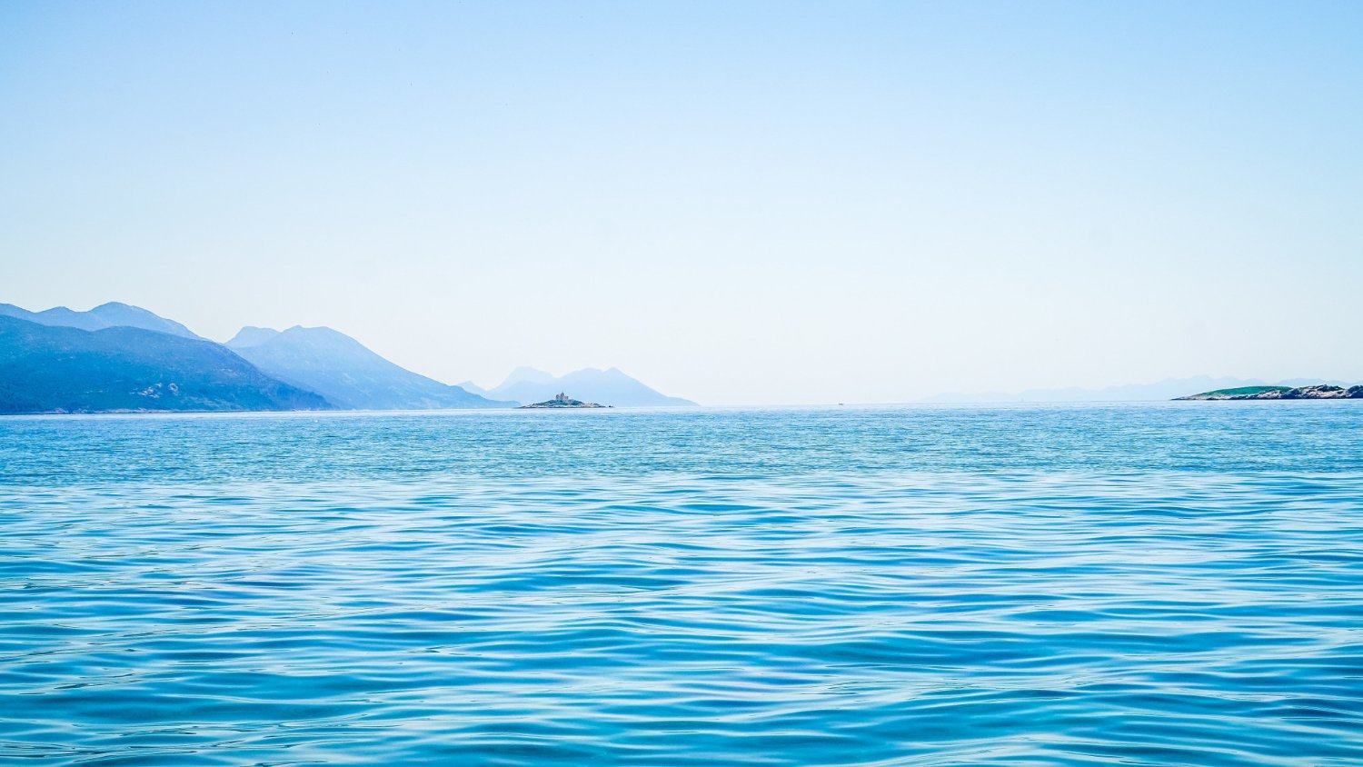 beautiful-shot-sea-with-mountain-distance-clear-sky